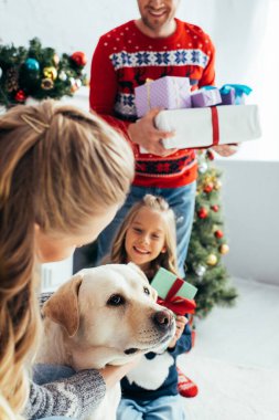 Noel 'de hediye almış bir kadın, kızının ve kocasının yanında köpeğe sarılıyor. 