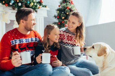 Noel 'de Labrador yakınlarında süveter giyen neşeli bir aile bardaklarını tutuyor. 