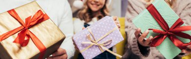 Noel Baba şapkalı neşeli aile Noel 'de hediyeler ve afişler taşıyor.