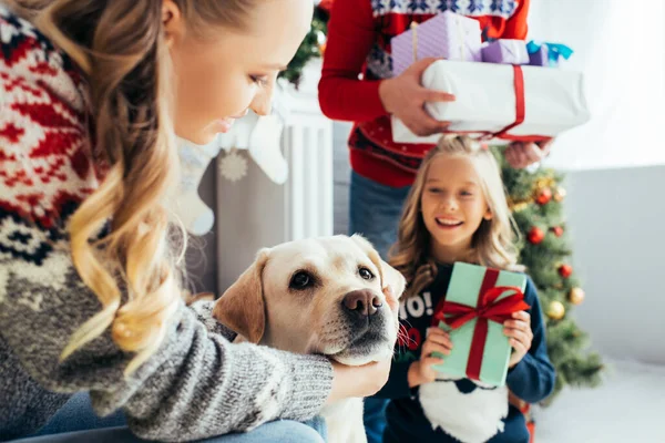 Mujer Feliz Abrazo Perro Con Borrosa Familia Fondo — Foto de Stock