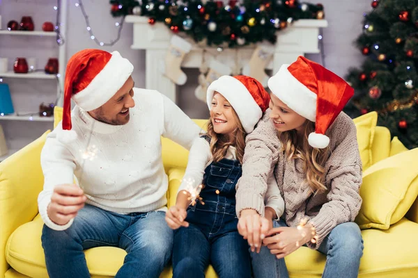 Szczęśliwa Rodzina Santa Kapelusze Gospodarstwa Ognie Urządzonym Salonie Boże Narodzenie — Zdjęcie stockowe