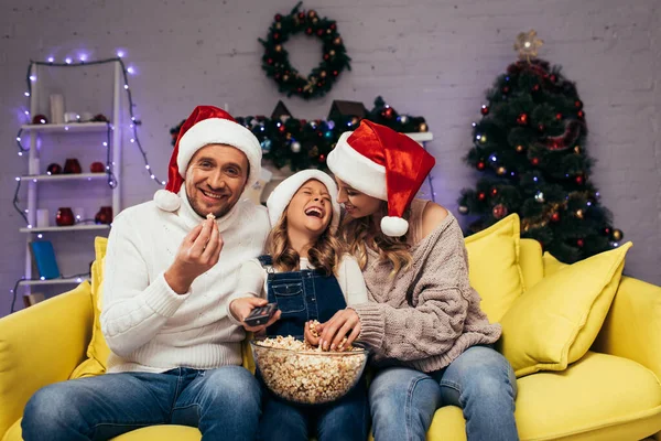 Glückliche Mutter Und Tochter Weihnachtsmannmützen Lachen Neben Mann Der Popcorn — Stockfoto