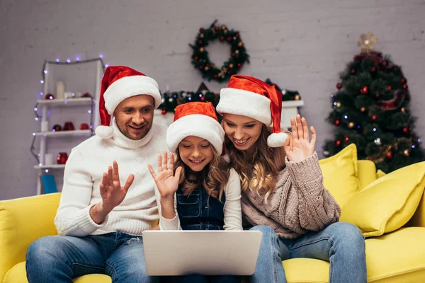 Freudige Familie Mit Weihnachtsmannmützen Winkende Hände Beim Videochat Dekorierten Wohnzimmer — Stockfoto