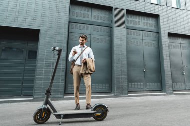 E- scooter ve binanın yanında dikilirken takım elbiseli iş adamlarının elinde akıllı telefon vardı. 