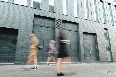 motion blur of people walking on street near grey building  clipart