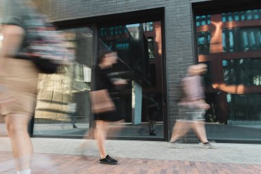 citizens walking on modern street near building, motion blur  clipart