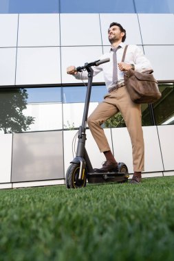 Resmi olarak mutlu iş adamları otların üzerinde elektrikli scooter 'ın yanında dikilirken 
