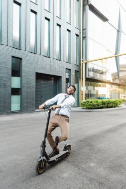 Resmi olarak hayretler içindeki işadamı bina yakınlarında elektrikli scooter kullanıyor. 