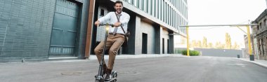 Bina ve pankartın yanında modern elektrikli scooter kullanan resmi giyimli iş adamı sayısı