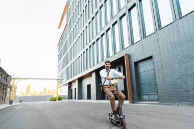 Binanın yakınında elektrikli scooter kullanan resmi olarak heyecanlı iş adamları. 