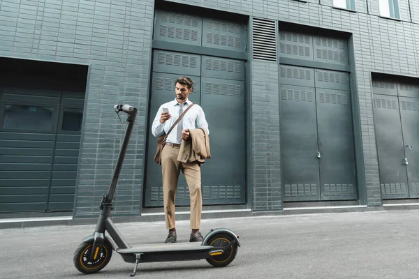 Full Length Businessman Suit Holding Smartphone While Standing Scooter Building — Stock Photo, Image