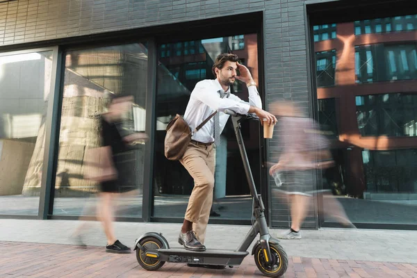 Nachdenklicher Geschäftsmann Auf Roller Hält Papierbecher Der Nähe Von Menschen — Stockfoto