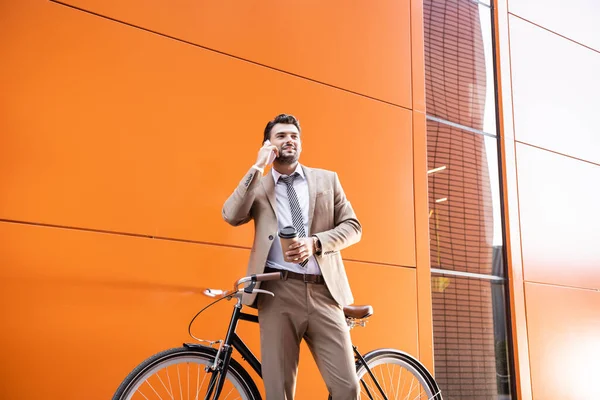 Homem Negócios Sorrindo Falando Smartphone Segurando Copo Papel Perto Bicicleta — Fotografia de Stock