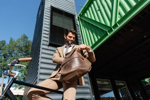 Low Angle View Cheerful Businessman Wireless Earphones Holding Leather Bag — Stock Photo, Image