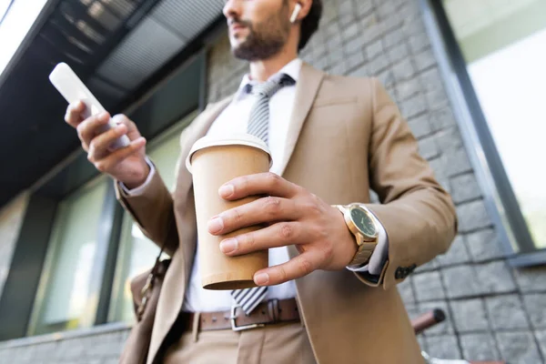 Cropped View Businessman Wireless Earphones Suit Holding Coffee Smartphone Building — Stock Photo, Image