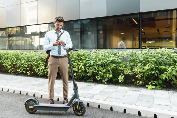 Full Length Businessman Texting Smartphone While Standing Scooter Plants Building — Stock Photo, Image