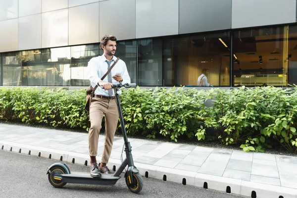 Geschäftsmann Hält Smartphone Der Nähe Von Scooter Anlagen Und Gebäude — Stockfoto