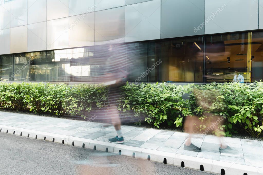 motion blur of people walking on street near modern building 
