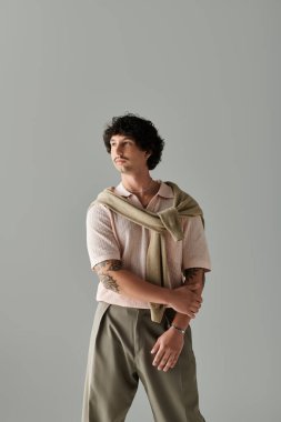 Genç adam minimalist bir stüdyoda, rahat bir duruşu, cazibesi ve tarzıyla duruyor..