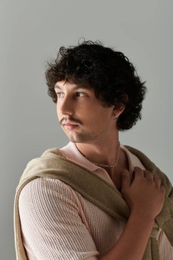 Şık bukleleri olan yakışıklı genç adam minimalist ortamda ileri moda bir görünüm sergiliyor..