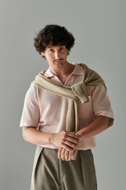 Yakışıklı genç adam rahat bir duruş ve düşünceli bir ifadeyle moda anlayışını sergiliyor..