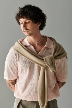 Modern moda giyinmiş yakışıklı bir genç, kendine güvenen bir poz ve şık detaylar sergiliyor..