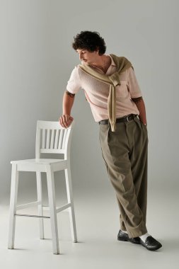 Genç adam, stüdyoda sandalyeye yaslanırken modern moda cazibesini sergiliyor..