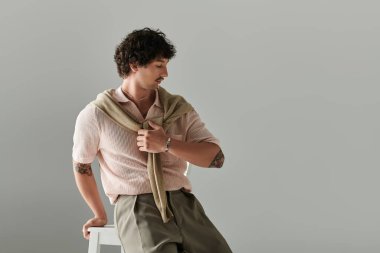 Moda kıyafetli yakışıklı genç adam minimalist bir arkaplana karşı rahat bir poz verdi.