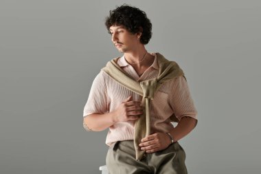 Sıradan giyinmiş şık bir genç adam kendine güvenen duruşuyla göze çarpar..