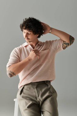 Yakışıklı genç bir adam, rahat bir pozla, yumuşak bir odada moda anlayışını sergiliyor..