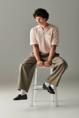 Yakışıklı genç bir adam şık bir stüdyoda otururken moda anlayışını sergiliyor..