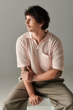 Yakışıklı genç bir adam modayı takip eden pastel bir elbiseyle huzurlu bir ortamda poz veriyor..