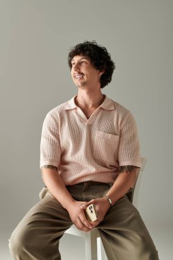 Şık giyinmiş yakışıklı genç adam sıcak bir şekilde gülümsüyor, zahmetsiz bir karizma ve tarz sergiliyor..