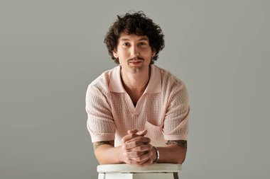 Yakışıklı genç adam, modern, tarafsız bir ortamda büyüleyici bir gülümsemeyle öne doğru eğiliyor..