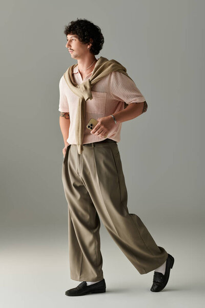 Handsome young man in contemporary attire confidently walks through a stylish studio space.