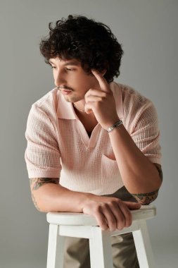 Yakışıklı bir adam, yumuşak ışıkla dolu modern bir ortamda poz verirken rahat bir tavır sergiler..