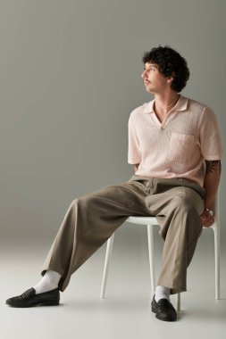 Yakışıklı genç adam, çağdaş uzayda zarif bir şekilde sandalyeye otururken eşsiz bir stil sergiliyor..