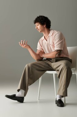 Şık giyinen genç adam özgüven ve yaratıcılık saçan düşünceli bir duruş sergiliyor..