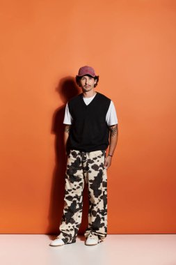 Yakışıklı bir genç dikkat çekici bir turuncu ayara güvenerek modaya uygun giysiler sergiliyor..