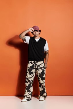 Yakışıklı genç adam modaya uygun kıyafetlerle poz veriyor. Çağdaş stili ve yeteneği vurguluyor..