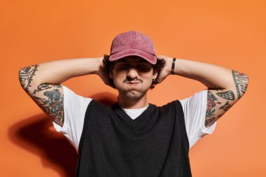 Kendine güvenen genç adam, kollarını başının arkasına koyarak eğlenceli bir poz verir. Tarzını vurgular..