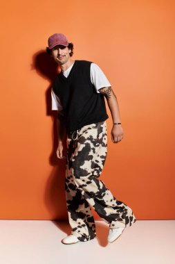 Şık genç adam modaya uygun kıyafetleri ve desenli pantolonları gösteriyor. Anın tadını çıkarıyor..