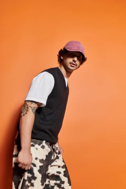 Yakışıklı genç adam sanatsal turuncu arka planıyla modern moda bir görünüm sergiliyor.