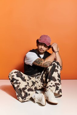 Yakışıklı genç adam modaya uygun bir şekilde poz veriyor, cesur şehir tarzı tercihlerini vurguluyor..