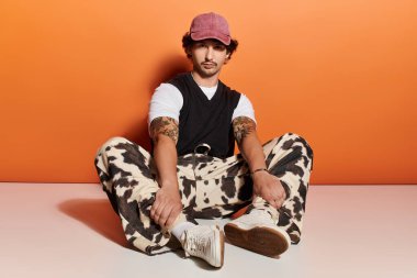 Rahat poz verip, tarzını ve tavırlarını sergileyen modaya uygun genç bir adam..