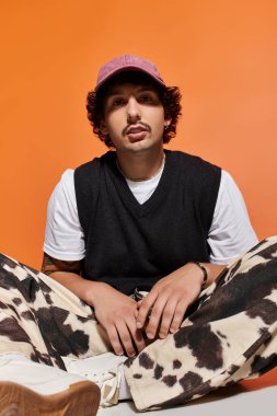 Yakışıklı bir genç adam rahat rahat oturur, kendine güvenerek eşsiz moda anlayışını sergiler..