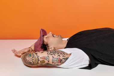 Dövmeli genç adam rahat bir anın tadını çıkarıyor. Eşsiz bir yerde kendine güveni ve cazibesi var..