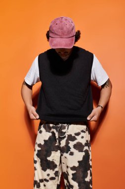 Yakışıklı bir adam gözünün önünde dikilip turuncu duvarlara bakarken şık kıyafetini düzeltir..