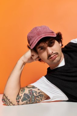 Yakışıklı genç bir adam rahat bir pozla rahatlar, modern stilini ve dövmesini vurgular..