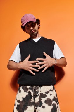 Yakışıklı genç adam moda gösterileri sergiliyor. Kapalı alanda cesur bir poz veriyor..